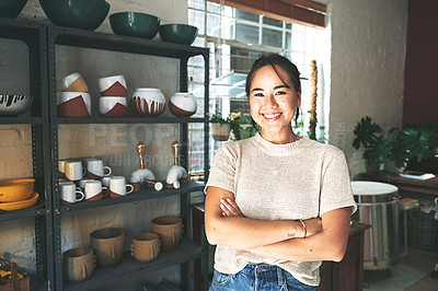 Buy stock photo Cropped portrait of an attractive young business owner standing alone in her pottery studio with her arms folded