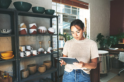 Buy stock photo Cropped portrait of an attractive young business owner standing alone in her pottery studio and using a tablet