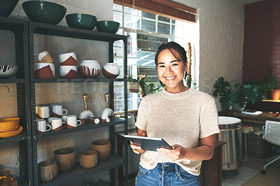 Buy stock photo Cropped portrait of an attractive young business owner standing alone in her pottery studio and using a tablet