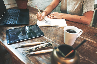 Buy stock photo Cropped shot of an unrecognizable business owner sitting alone in her pottery studio and making notes