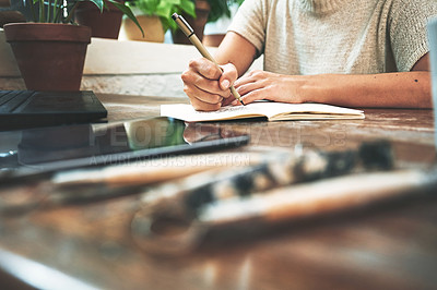 Buy stock photo Cropped shot of an unrecognizable business owner sitting alone in her pottery studio and making notes