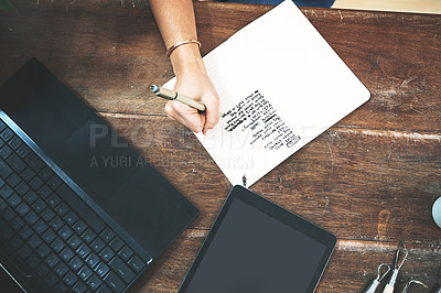 Buy stock photo High angle shot of an unrecognizable business owner sitting alone in her pottery studio and making notes