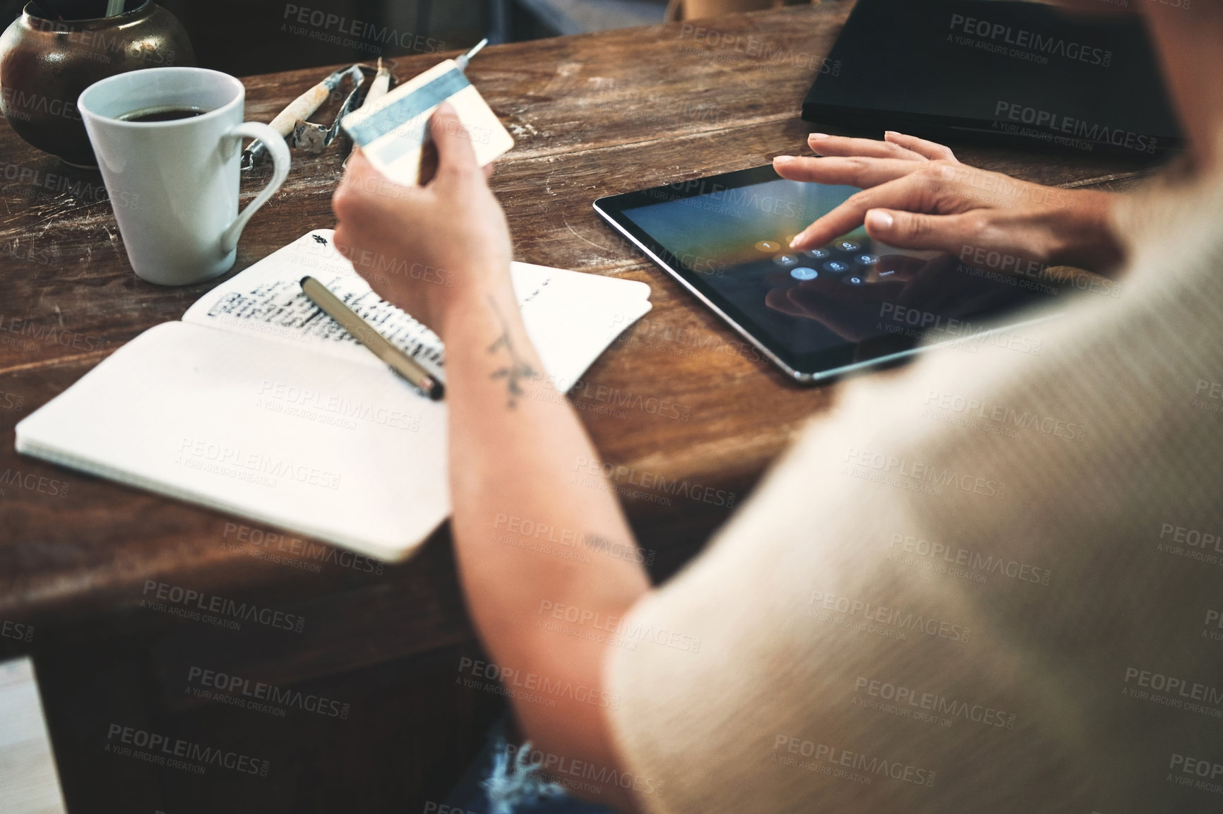 Buy stock photo Cropped shot of an unrecognizable business owner sitting alone in her studio and using a tablet for online shopping