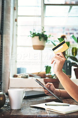 Buy stock photo Cropped shot of an unrecognizable business owner sitting alone in her studio and using a tablet for online shopping