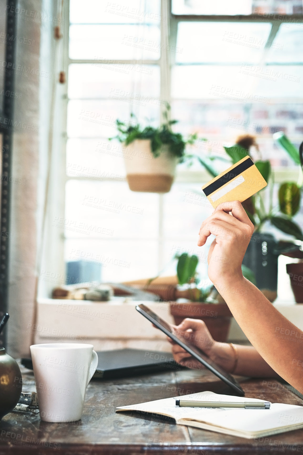 Buy stock photo Cropped shot of an unrecognizable business owner sitting alone in her studio and using a tablet for online shopping