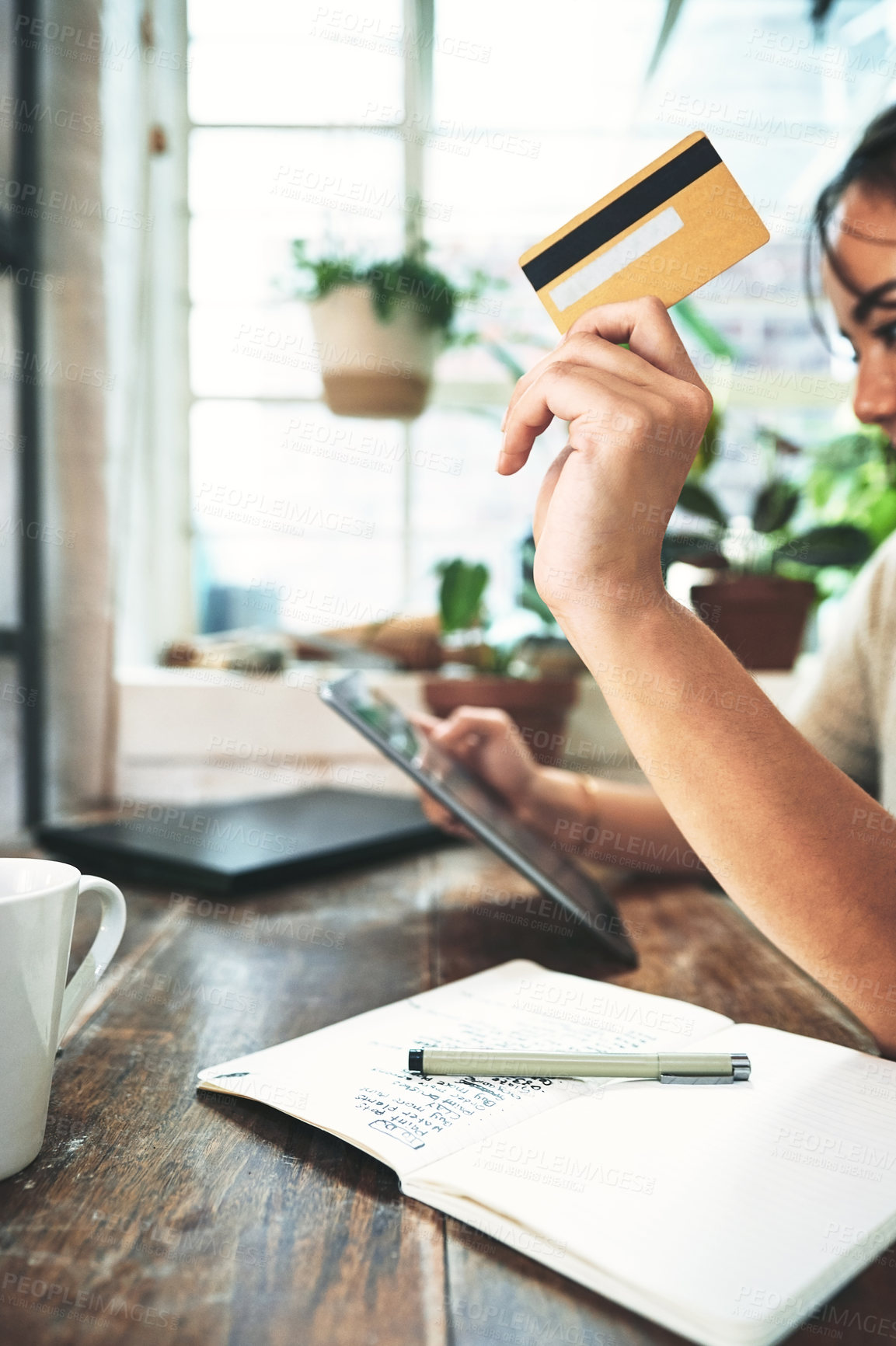 Buy stock photo Cropped shot of an unrecognizable business owner sitting alone in her studio and using a tablet for online shopping