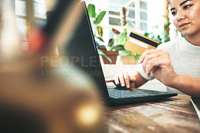 Buy stock photo Cropped shot of an attractive young business owner sitting alone in her studio and using a laptop for online shopping