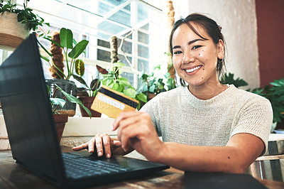 Buy stock photo Cropped portrait of an attractive young business owner sitting alone in her studio and using a laptop for online shopping