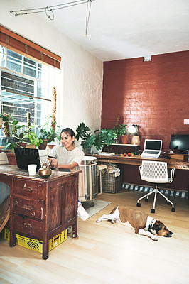 Buy stock photo Cropped shot of an attractive young business owner sitting alone in her studio and using a laptop for online shopping