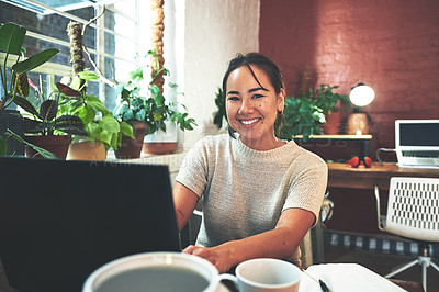 Buy stock photo Cropped portrait of an attractive young business owner sitting alone in her pottery studio and using her laptop