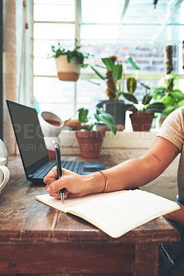 Buy stock photo Cropped shot of an unrecognizable business owner sitting alone in her pottery studio and making notes