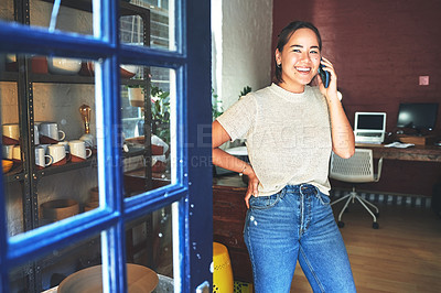 Buy stock photo Cropped shot of an attractive young business owner standing alone in her pottery studio and using her cellphone