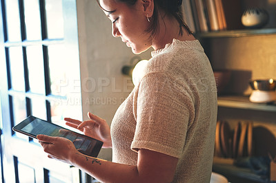 Buy stock photo Cropped shot of an attractive young business owner standing alone in her pottery studio and using a tablet