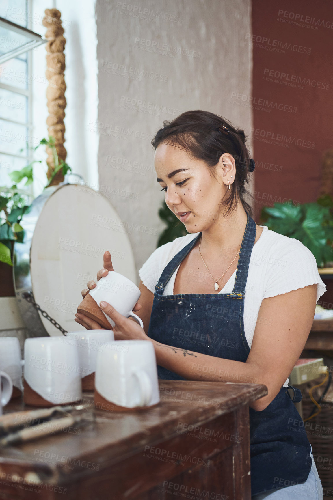 Buy stock photo Shot of a young woman making mugs in a pottery studio