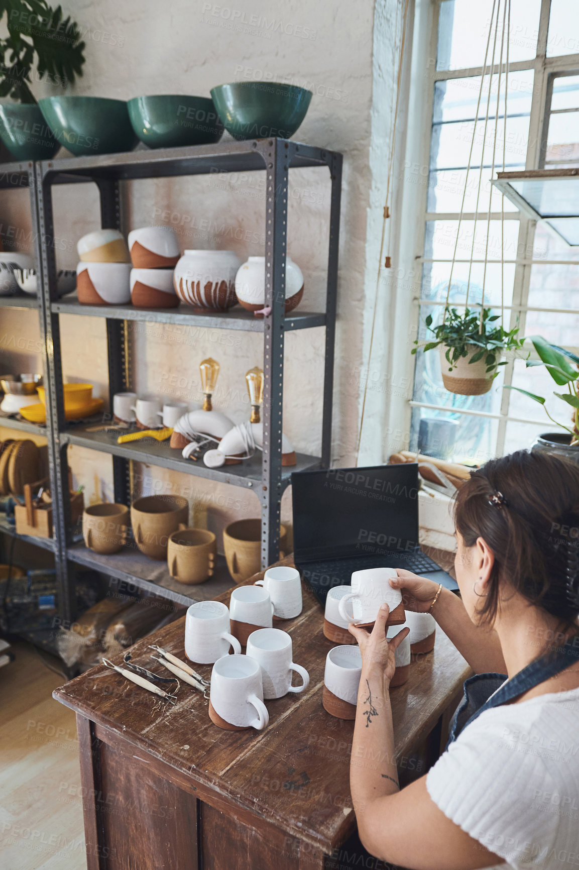 Buy stock photo Shot of a young woman making mugs in a pottery studio