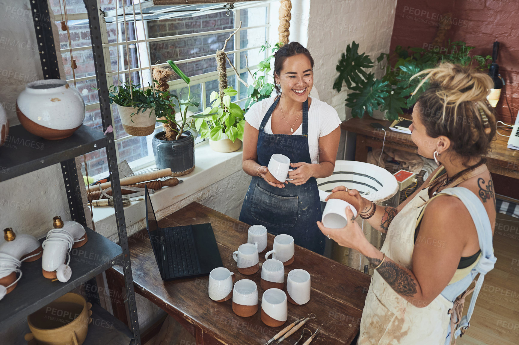 Buy stock photo Shot of two young women making mugs in a pottery studio