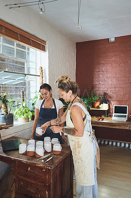 Buy stock photo Shot of two young women making mugs in a pottery studio