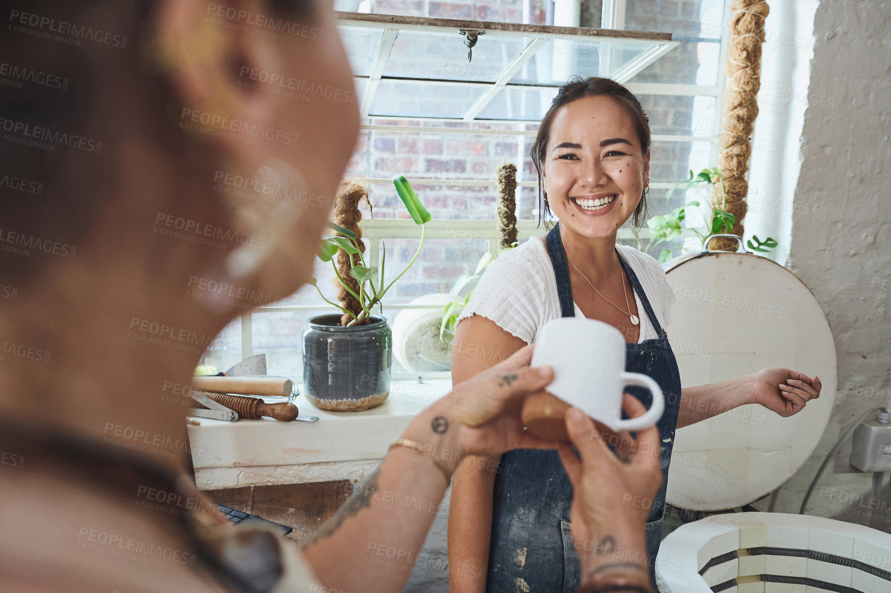 Buy stock photo Shot of two young women using an electric kiln in a pottery studio