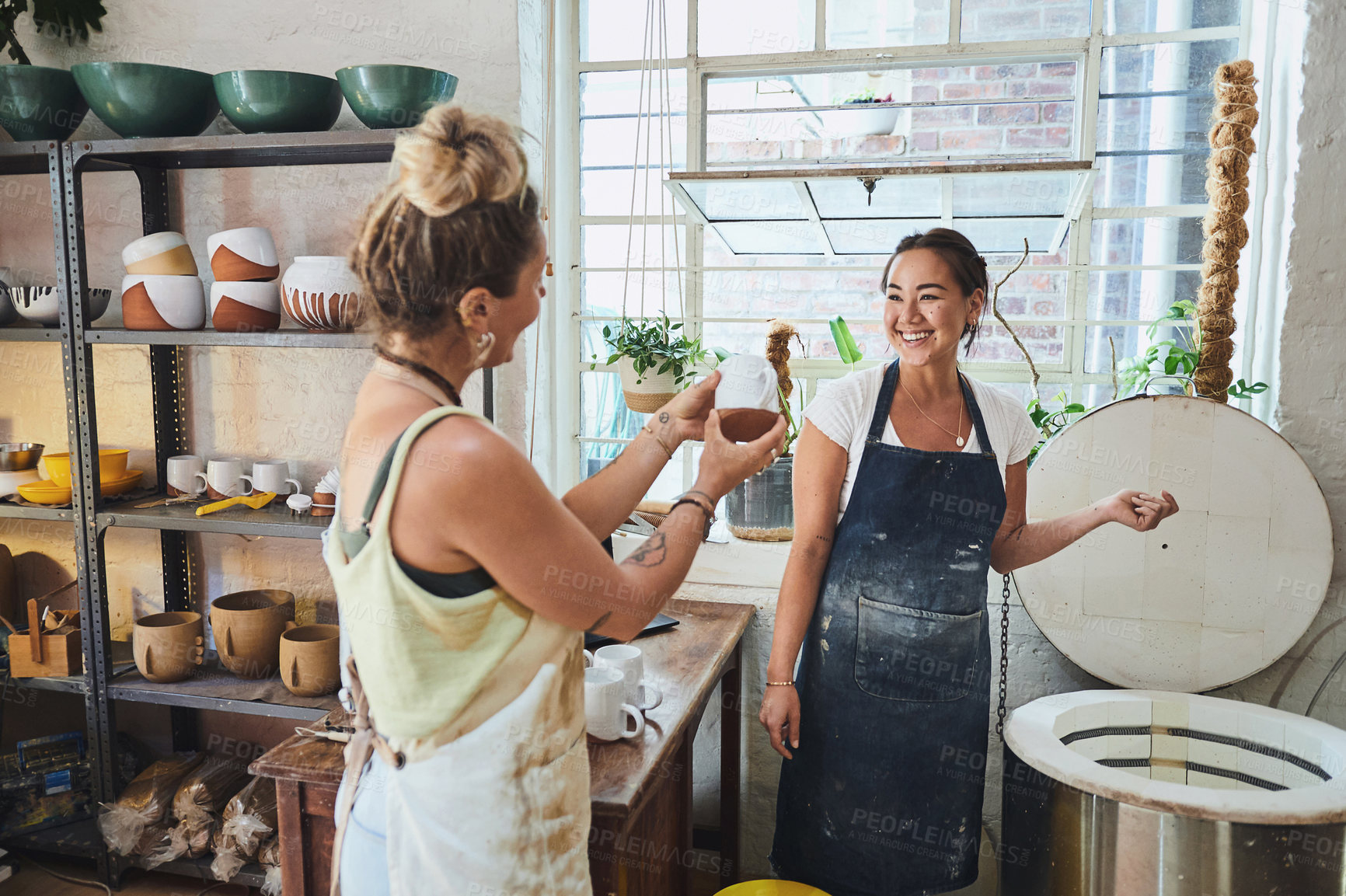 Buy stock photo Shot of two young women using an electric kiln in a pottery studio