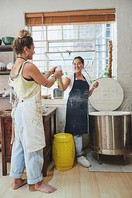 Buy stock photo Shot of two young women using an electric kiln in a pottery studio