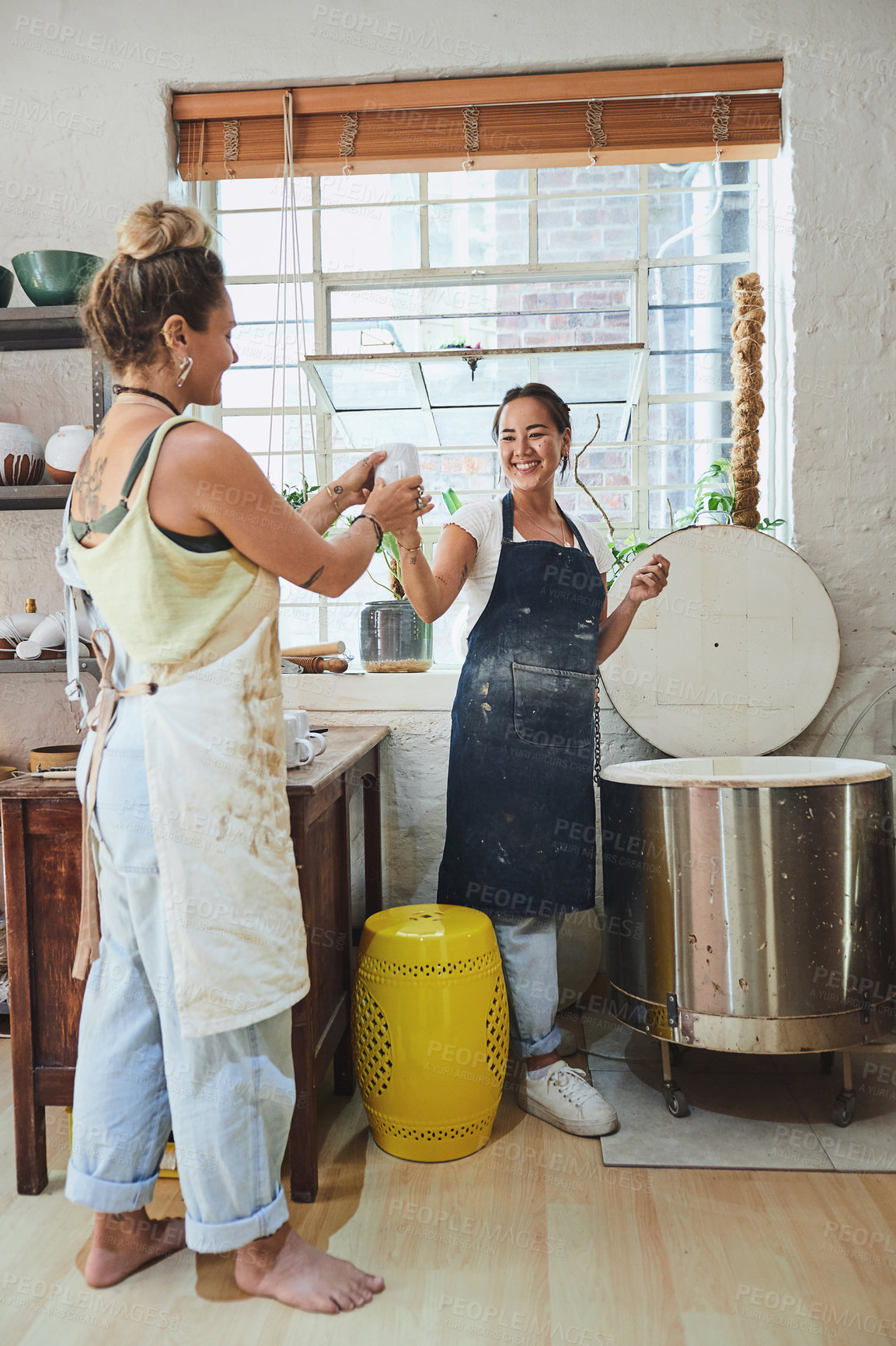 Buy stock photo Shot of two young women using an electric kiln in a pottery studio