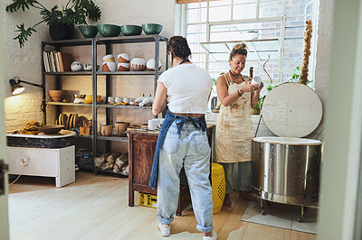 Buy stock photo Shot of two young women using an electric kiln in a pottery studio