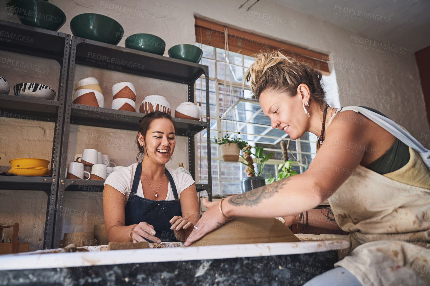 Buy stock photo Shot of two young women working with clay in a pottery studio