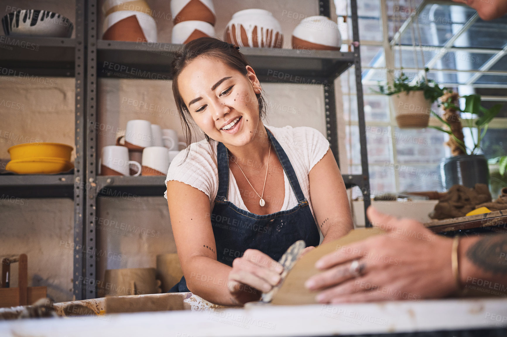 Buy stock photo Shot of two young women working with clay in a pottery studio