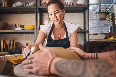 Buy stock photo Shot of two young women working with clay in a pottery studio