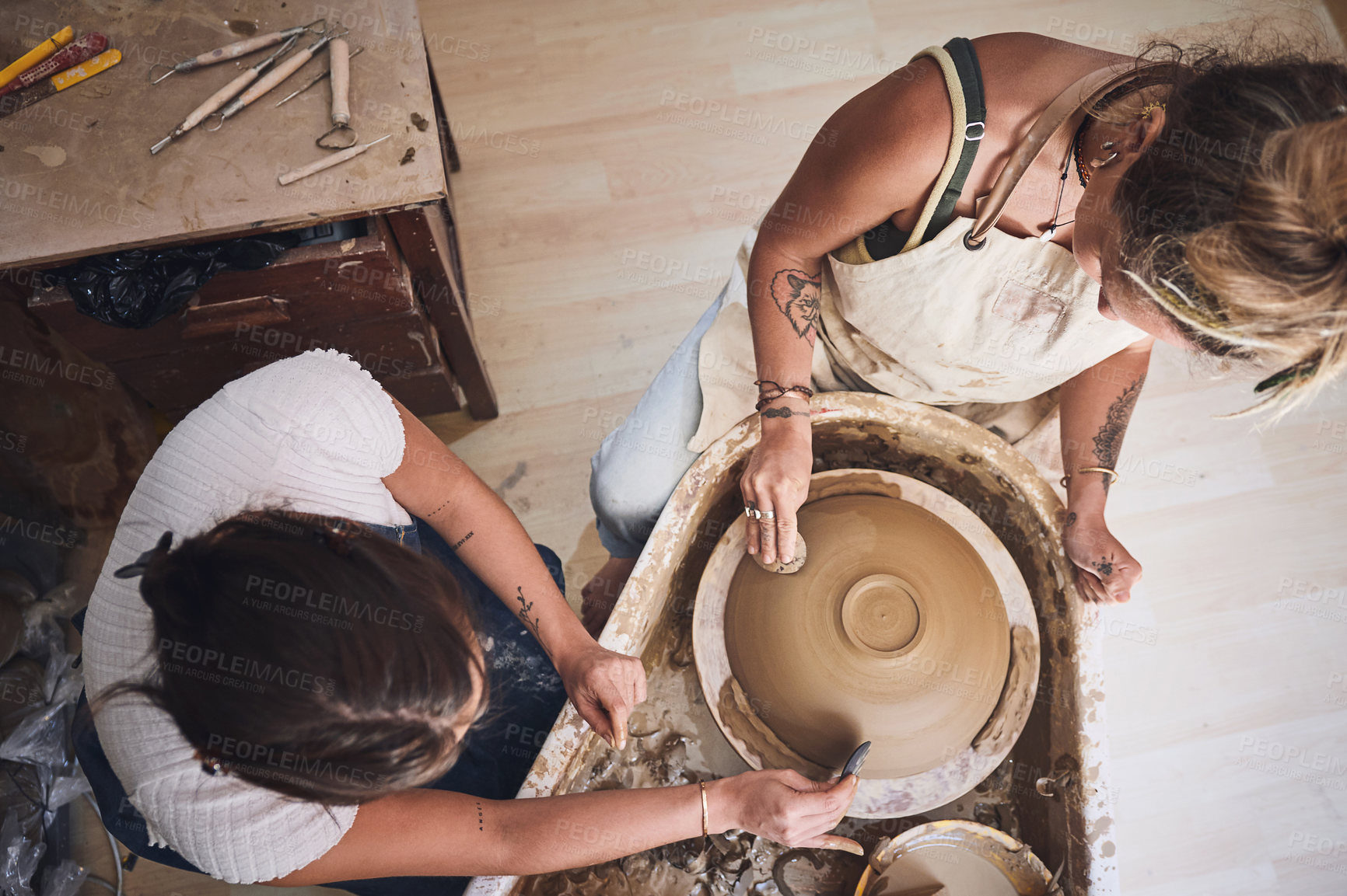 Buy stock photo Shot of two young women working with clay in a pottery studio