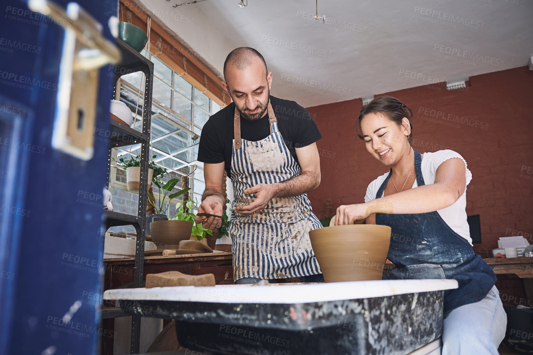 Buy stock photo Shot of a young man and woman working with clay in a pottery studio