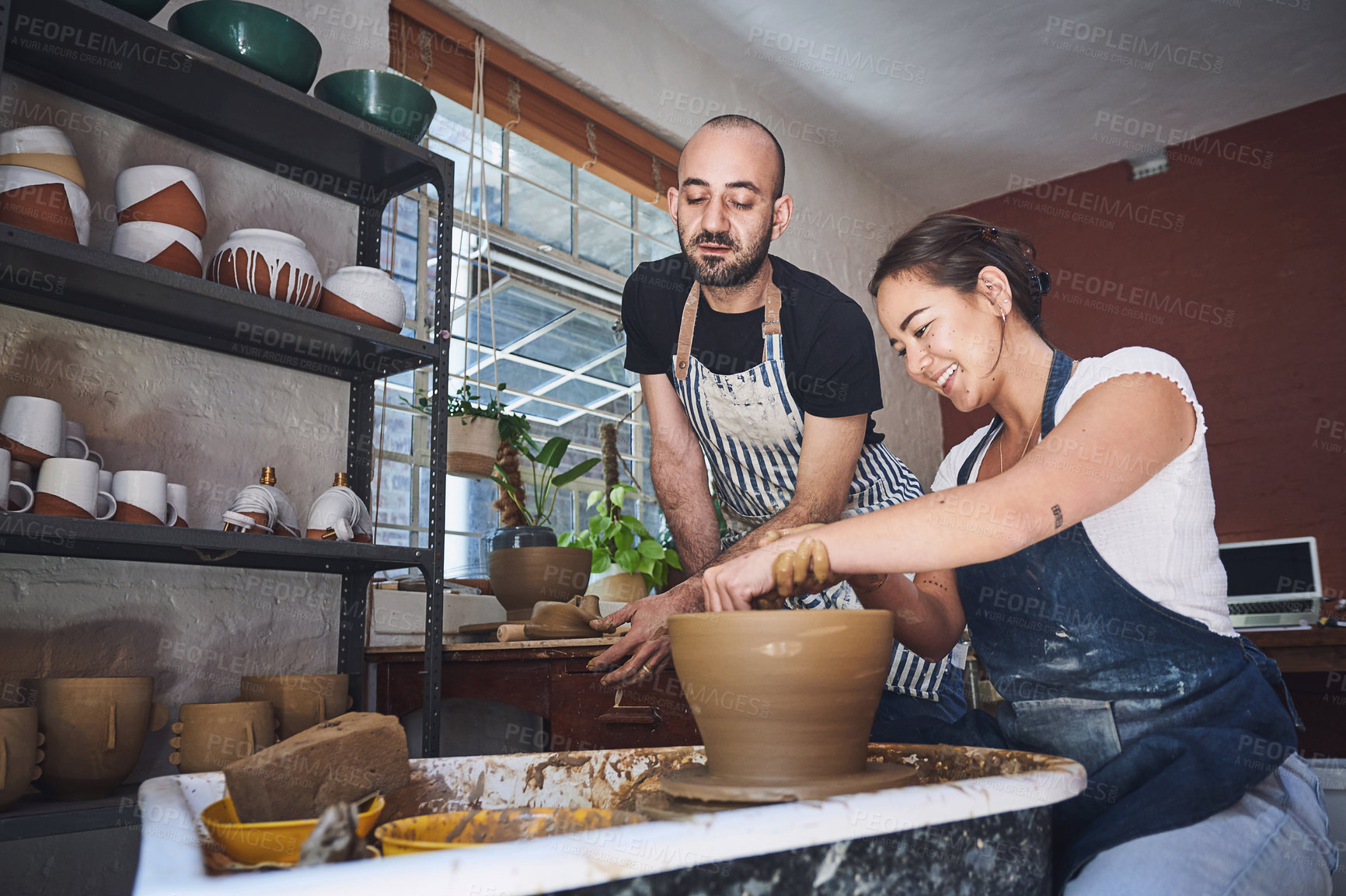 Buy stock photo Shot of a young man and woman working with clay in a pottery studio