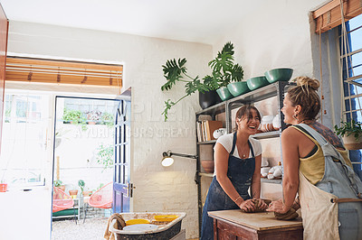 Buy stock photo Shot of two young women kneading clay in a pottery studio