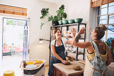 Buy stock photo Shot of two young women giving each other a high five in a pottery studio