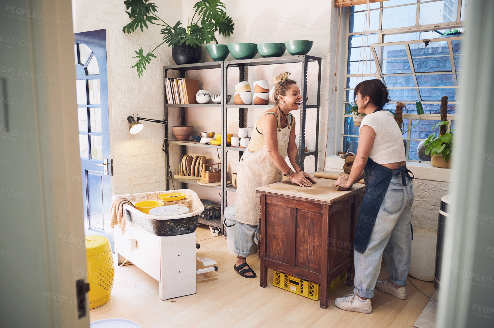 Buy stock photo Shot of two young women kneading clay in a pottery studio