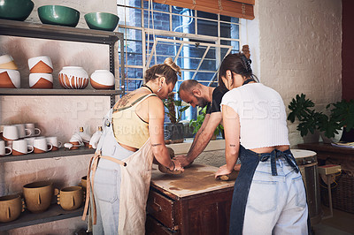 Buy stock photo Shot of a group of young people kneading clay in a pottery studio