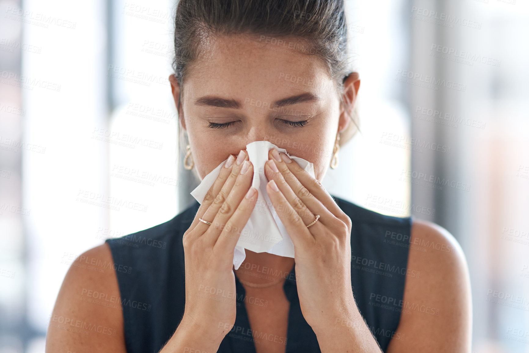 Buy stock photo Shot of a young businesswoman blowing her nose in an office