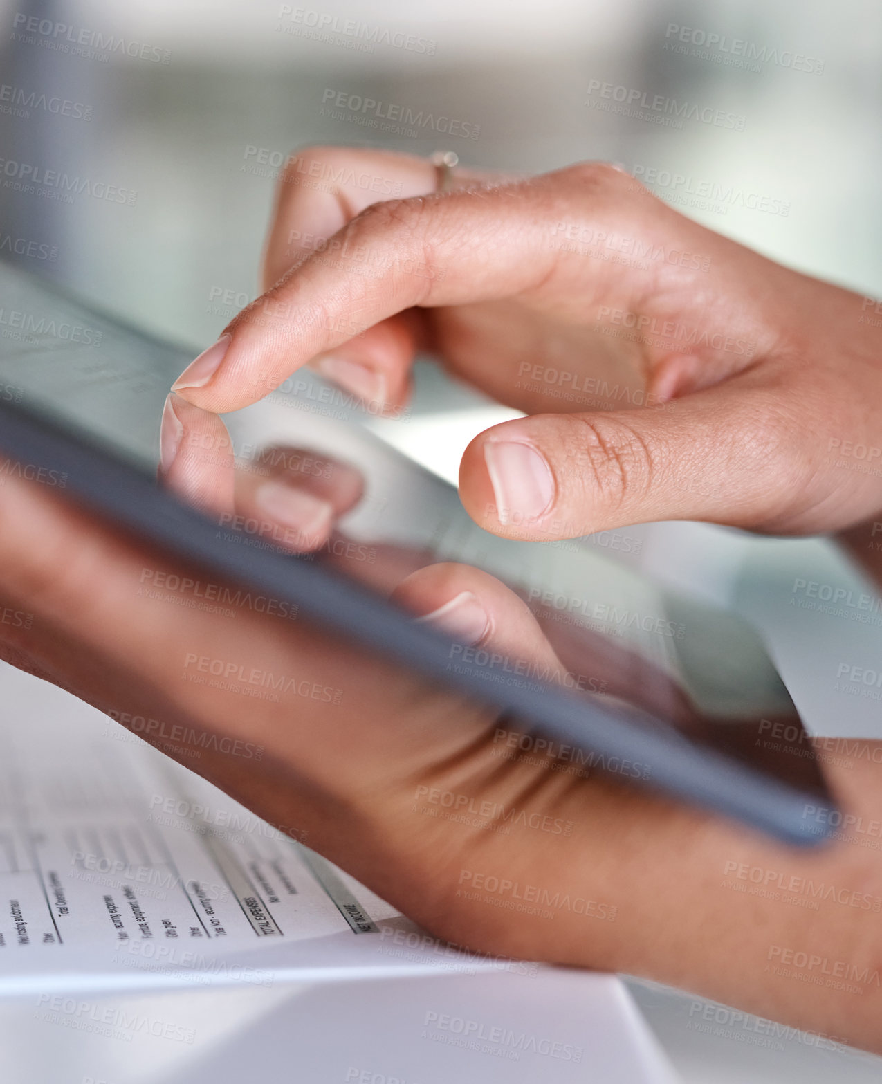 Buy stock photo Closeup shot of an unrecognisable businesswoman using a digital tablet while going through paperwork in an office