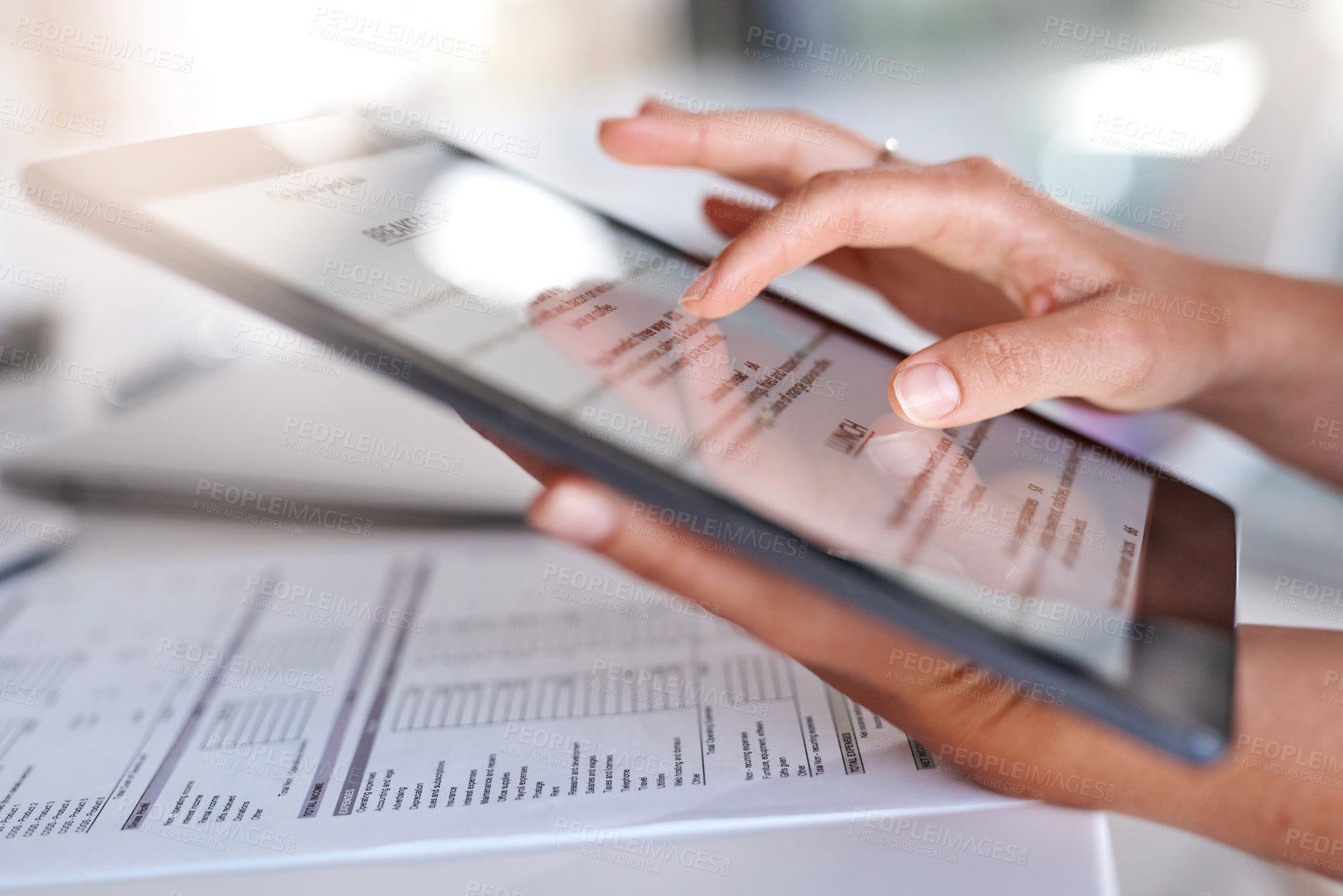 Buy stock photo Closeup shot of an unrecognisable businesswoman using a digital tablet while going through paperwork in an office