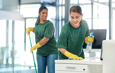 Buy stock photo Shot of two young woman cleaning a modern office