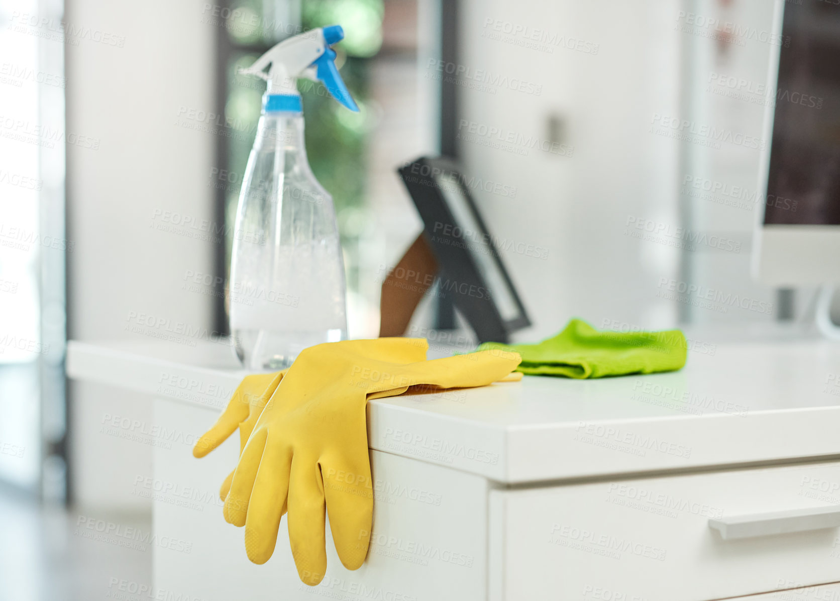Buy stock photo Shot of a pair of rubber gloves and disinfectant spray on a desk in a modern office