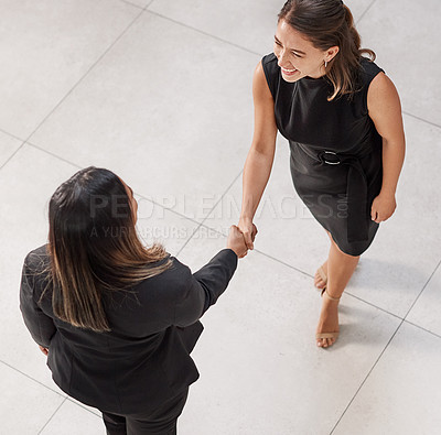 Buy stock photo High angle shot of two businesswomen shaking hands in an office