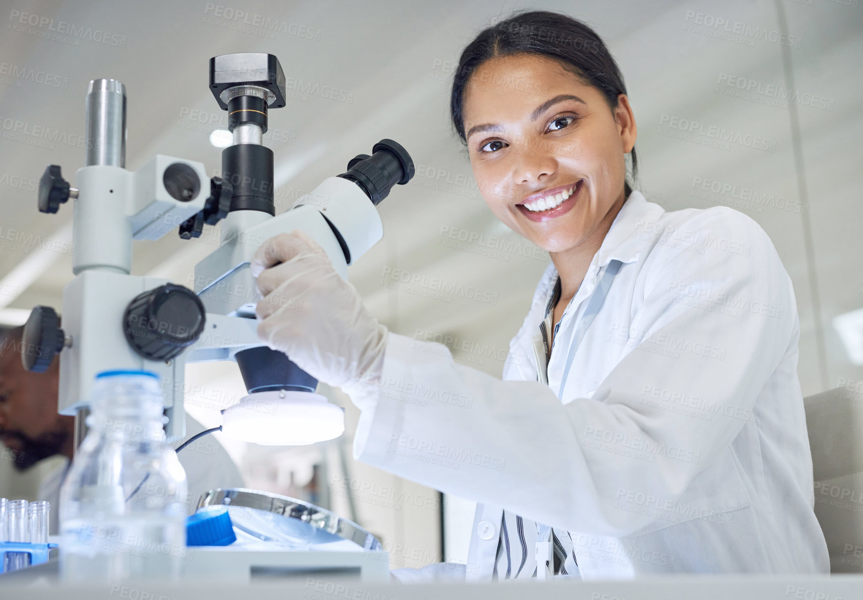 Buy stock photo Portrait of a young scientist using a microscope in a lab