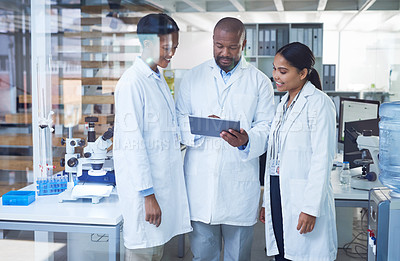 Buy stock photo Shot of a group of scientists using a digital tablet in a laboratory