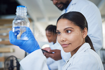 Buy stock photo Shot of a young scientist conducting research with her team in a laboratory