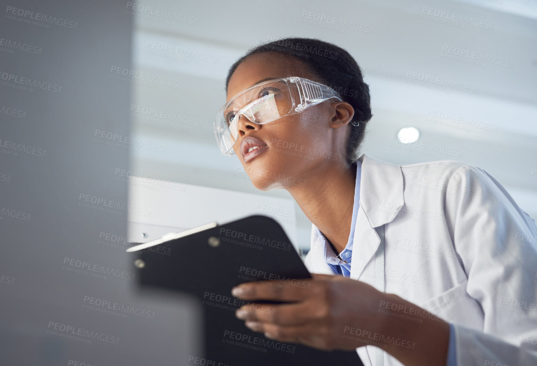 Buy stock photo Shot of a young scientist using a computer while conducting research in a laboratory
