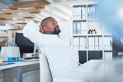 Buy stock photo Shot of a scientist taking a break at his desk while conducting research in a laboratory