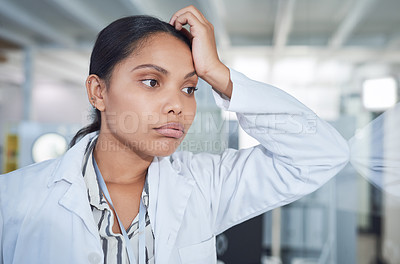 Buy stock photo Shot of a young scientist looking stressed while conducting research in a laboratory