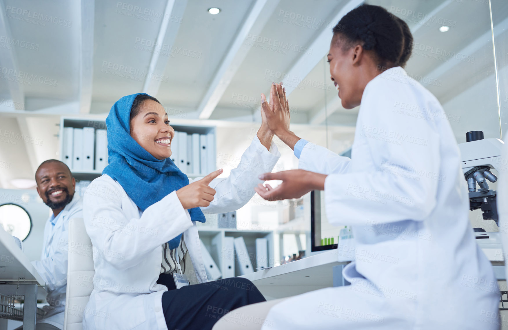 Buy stock photo Shot of two scientists giving each other a high five while conducting research in a laboratory