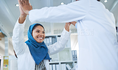 Buy stock photo Shot of two scientists giving each other a high five while conducting research in a laboratory